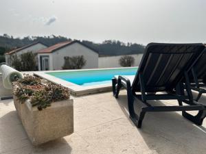 a black chair sitting on a patio next to a pool at VillaVie CostadePrata in Alfeizerão