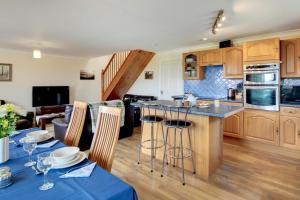 a kitchen with wooden cabinets and a kitchen island with bar stools at 4 Bed in Upton Cross oc-j34643 in Upton