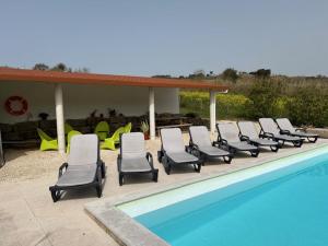 a row of lounge chairs next to a swimming pool at VillaVie CostadePrata in Alfeizerão
