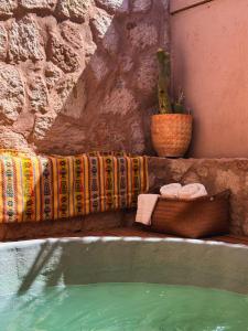a swimming pool with a bench with towels and a plant at Casa Lickana B&B in San Pedro de Atacama