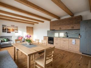 a kitchen and living room with a wooden table and chairs at Panorama Suite am Marschbachhof in Walchsee