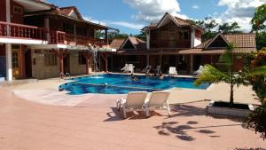 a swimming pool with two chairs in front of a house at Hosteria Don Elias in Puyo