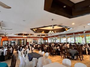a large room with a large group of people sitting at tables at Hotel Pasabien in Huité