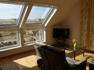 a living room with two large windows and a television at Pension Feuerschiff in Borkum