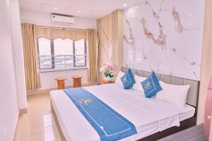 a bedroom with a bed with blue pillows and a window at Cat Ba Bay Vision Hotel in Cat Ba