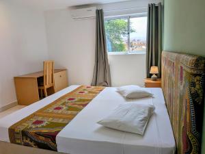 a bedroom with a white bed with a window at Hotel Strela Tarrafal in Tarrafal