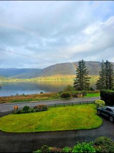 a rainbow over a lake with a car on a road at The Hideaway Guest suite in Fort William