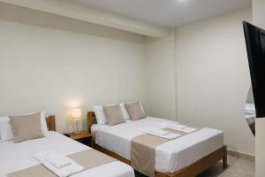 a room with two beds and a flat screen tv at studio confort in Iquitos