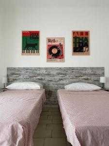 two beds in a room with paintings on the wall at Casa Camilla in Lido di Fermo
