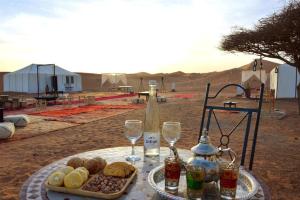a table with a tray of food and wine glasses at Erg Chebbi Traditional Experience & Activities in Merzouga