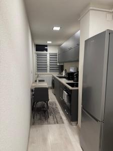 a kitchen with a refrigerator and a table with a chair at Barney Apartman in Sovata