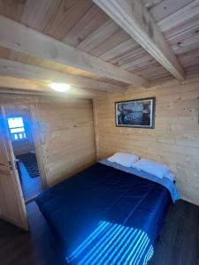 a large blue bed in a wooden cabin at Horseshoe Lake Beachside Cottage in Parry Sound