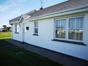 a white house with windows on the side of it at Notre Petit Chateau in Rosslare Harbour