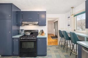 a kitchen with blue cabinets and a stove and chairs at Private Riverside Retreat in Appleton