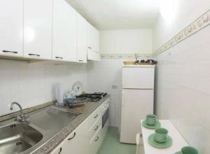 a white kitchen with a sink and a refrigerator at Sardinia Re - Grecale 25 in Porto Rotondo