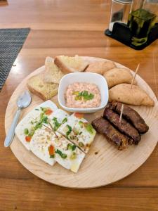 a plate of food with eggs sausage and bread at Hotel Strela Tarrafal in Tarrafal