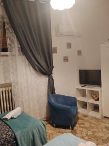 a bedroom with a blue chair and a television at Casa di Ana 2 affittacamere in Ancona