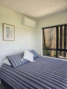 a bedroom with a blue and white striped bed and a window at Studio with amazing views in Russell