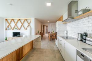 a kitchen with white counter tops and wooden cabinets at Casas do Forneiro - T2 in Nordeste