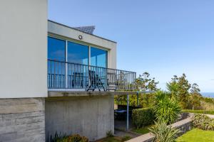 a house with a balcony with chairs on it at Casas do Forneiro - T2 in Nordeste