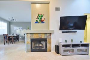a living room with a fireplace and a flat screen tv at Lighted Pool Nights Fenced Yard & Mountain View in Tucson