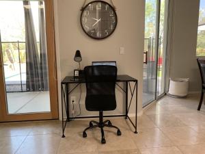 a desk with a chair and a clock on the wall at Lighted Pool Nights Fenced Yard & Mountain View in Tucson +31 photos