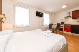 a white bedroom with a white bed and a kitchen at NEW Appartamenti Anna in Sirmione +27 photos
