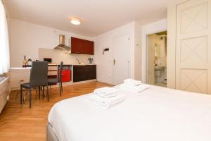 a bedroom with a white bed and a kitchen at NEW Appartamenti Anna in Sirmione