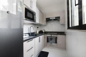 a kitchen with white cabinets and a sink and a microwave at شاليهات وفلل سُبات in Half Moon Bay