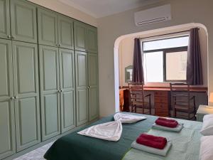 a bedroom with green cabinets and a bed with two towels at Panoramic XL Penthouse Sliema Seafront in Sliema
