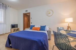 a bedroom with a bed with blue sheets and a table at PRESTIGE Apartments - Blue Serenity in Verona
