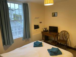 a bedroom with a bed and a desk and a window at George and Dragon Dent in Dent