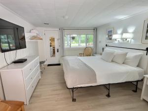 a bedroom with a large white bed and a tv at Kennebunkport Motor Lodge in Kennebunkport