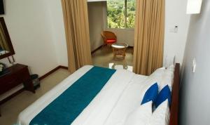 a bedroom with a bed with a blue and white blanket at The Villa Rochelle Kandy in Kandy