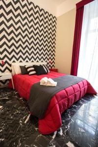 un letto rosso in una stanza con parete a scacchi di B&B Rettifilo a Napoli