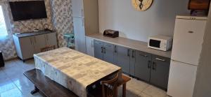 a kitchen with a table and a white refrigerator at gite climatisé jusqu'à 9 personnes secteurs la broque Obernai Strasbourg in La Broque