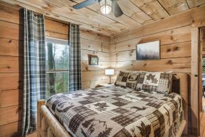 a log cabin bedroom with a bed and a window at Dog friendly, Hot Tub & Near Tuckaleechee Caverns in Townsend