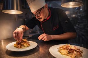 a chef preparing food on a plate on a counter at Hotel Europa in Quiberon