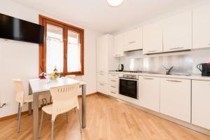a kitchen with white cabinets and a table and chairs at Anna Home View in Sirmione