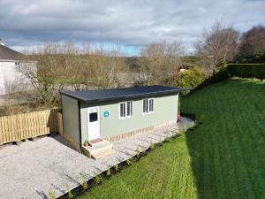 a small shed with a black roof in a yard at 1 Bedroom Lodge By Travel Lets Self Catering Accommodation Rathmullen With Hot Tub in Ramelton