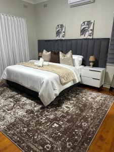 a bedroom with a large bed and a rug at Phela Guesthouse in Edenvale +17 photos