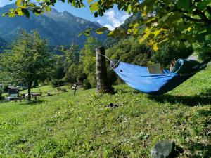 a person sleeping in a hammock with a book at Casa Davide Valdaone in Daone