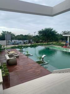 a large swimming pool with chairs and a wooden deck at Cozy 1BR with Balcony, Sea View and Pool - Fast WiFi - Snug Sanctuary in Talisay