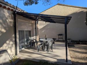 a patio with a table and chairs under a pergola at À l'ombre du pin in Entraigues-sur-la-Sorgue