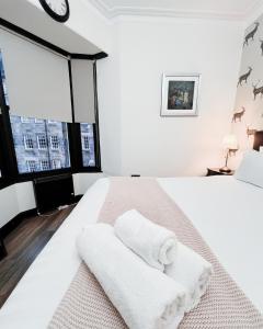 a white bedroom with a bed with towels on it at Old Town Castle Apartment in Edinburgh