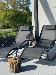 two chairs sitting on a porch with a tree stump at Domek z jacuzzi Studnica 39 in Studnica