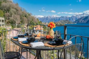 a table on a balcony with a view of the water at Alba on Lake Como by Rent All Como in Sala Comacina