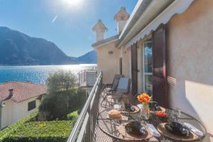 a table on a balcony with a view of the water at Alba on Lake Como by Rent All Como in Sala Comacina +29 photos