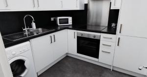 a kitchen with white cabinets and a sink and a dishwasher at New Town Residence in Edinburgh