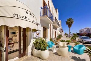 a building with blue and white pots on the sidewalk at Araba Fenice Hotel in San Vito lo Capo